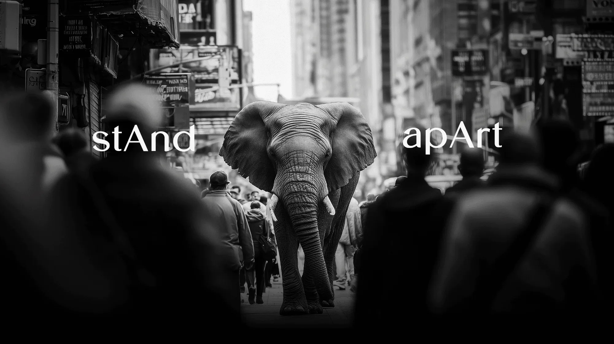 An elephant walking through a crowded street under a stAnd apArt billboard